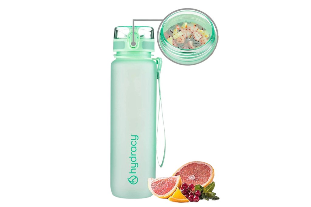 Botella verde claro para beber Hydracy sobre un fondo blanco con un inserto de burbuja detallado con fruta cortada y un pomelo cortado por la mitad junto a él