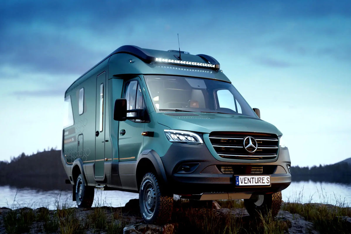 Camper Van mit Outdoor-Eigenschaften wie hohem Radstand und Crossreifen auf Messestand. Seitlich von vorn abgelichtet.