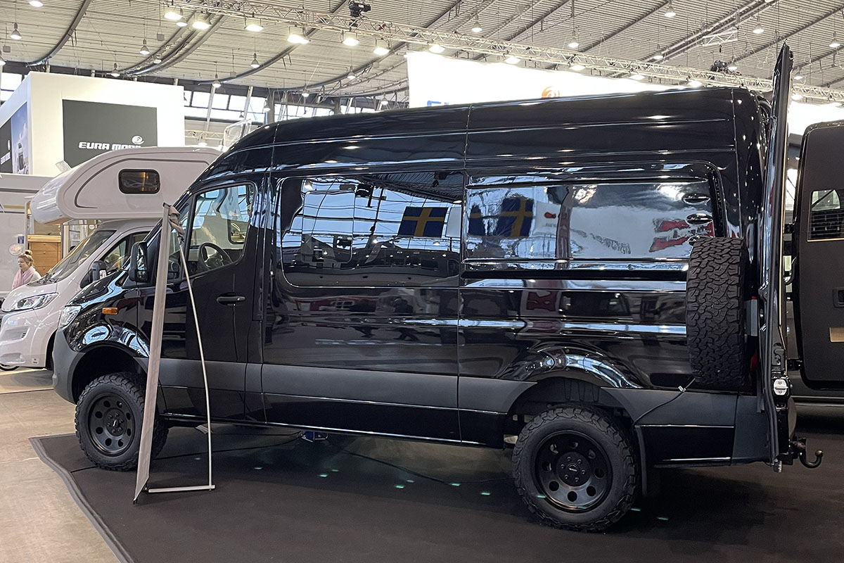 Camper Van mit Outddor-Eigenschaften wie hohem Radstand und Crossreifen auf Messestand.