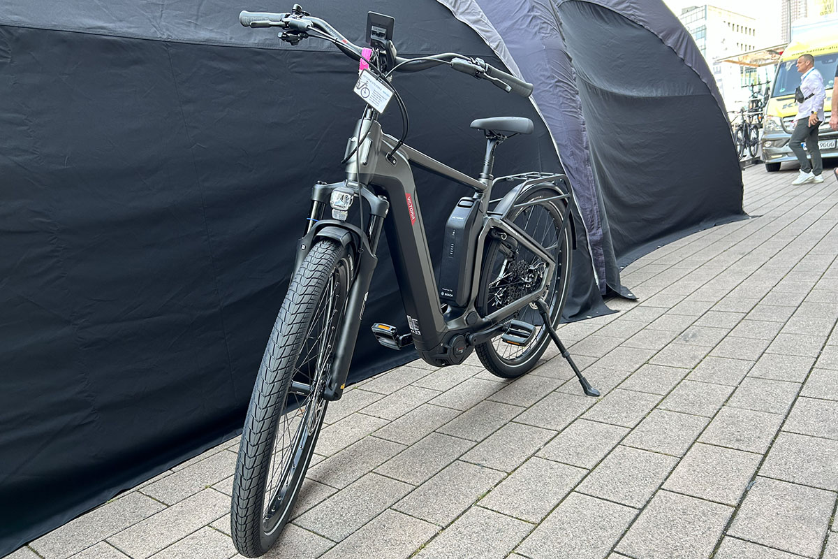 E-Bike Victoria Utilyon in Frontansicht (leicht schräge) vor Messestand auf der Eurobike 2023.