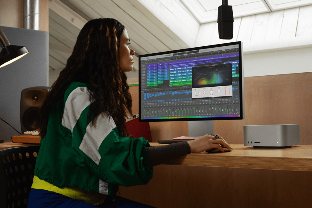 Ein Frau arbeitet an einem Bildschirm, rechts ein Mac Studio