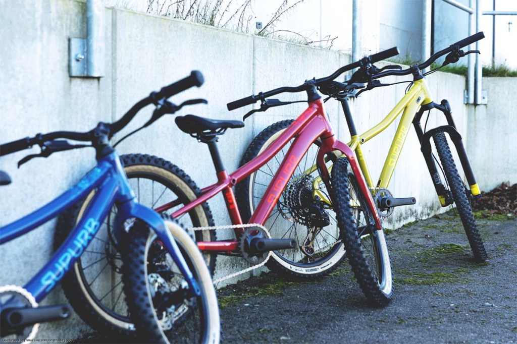 Drei Kinderfahrräder in verschiedenen Farben nebeneinander