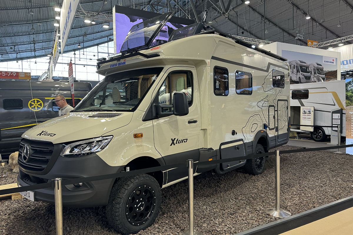 Camper Van mit Outddor-Eigenschaften wie hohem Radstand und Crossreifen auf Messestand.