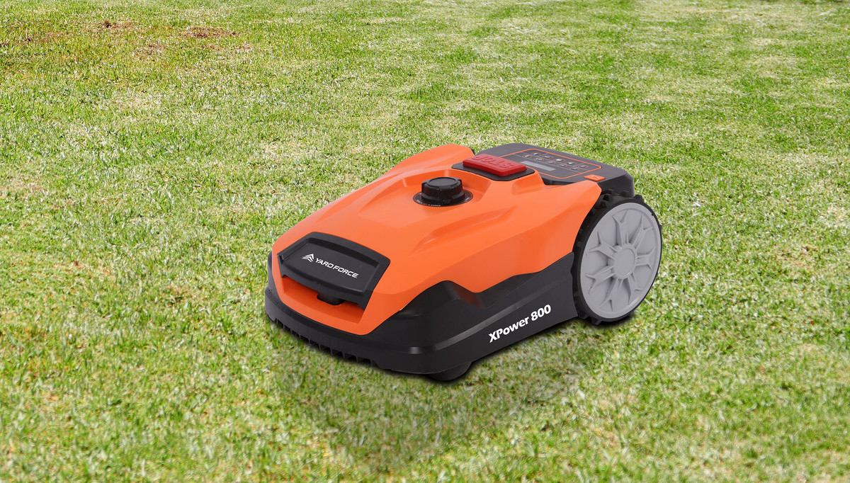 Orange schwarzer Yard-Force-Mähroboter schräg von vorne auf grünem Rasen