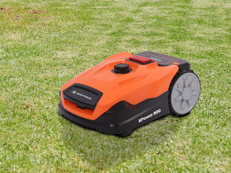 Orange schwarzer Yard-Force-Mähroboter schräg von vorne auf grünem Rasen