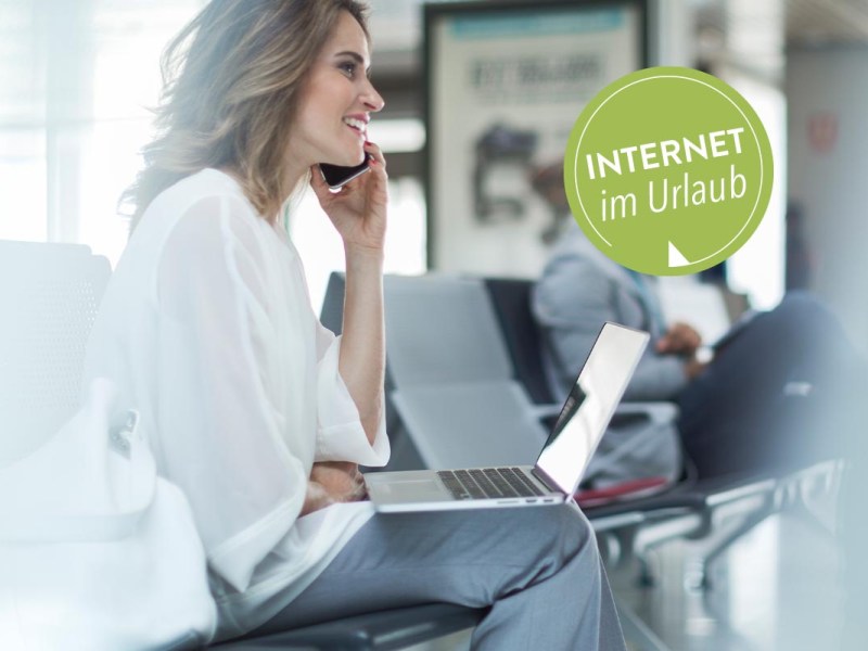 Eine Frau sitzt mit Smartphone und Notebook am Flughafen