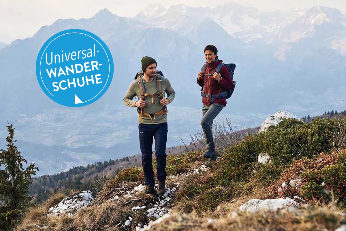 Zwei Personen wandern auf einem Hügel.