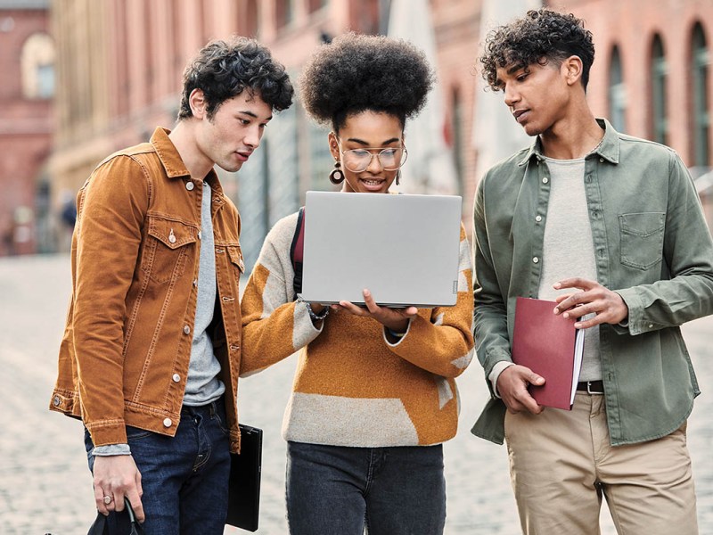 Drei junge Menschen schauen auf ein Laptop.