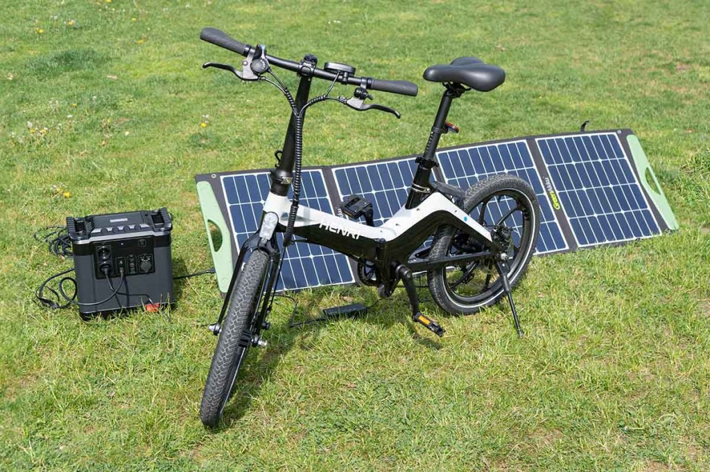 Ein E-Bike lädt an einer Powerstation mit Solarpanel.