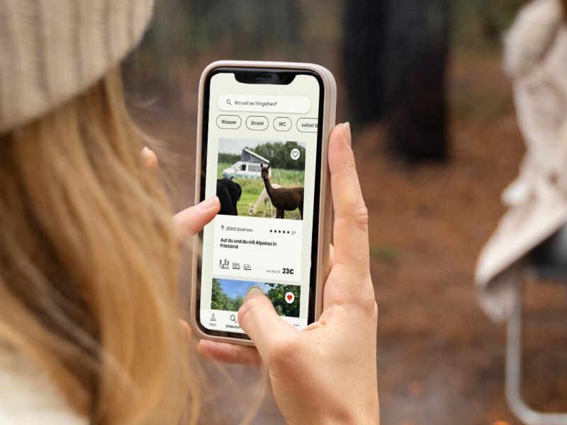 Overshoulder-Blick auf ein Smartphone, man sieht, wie die Person nach Campingplätzen sucht
