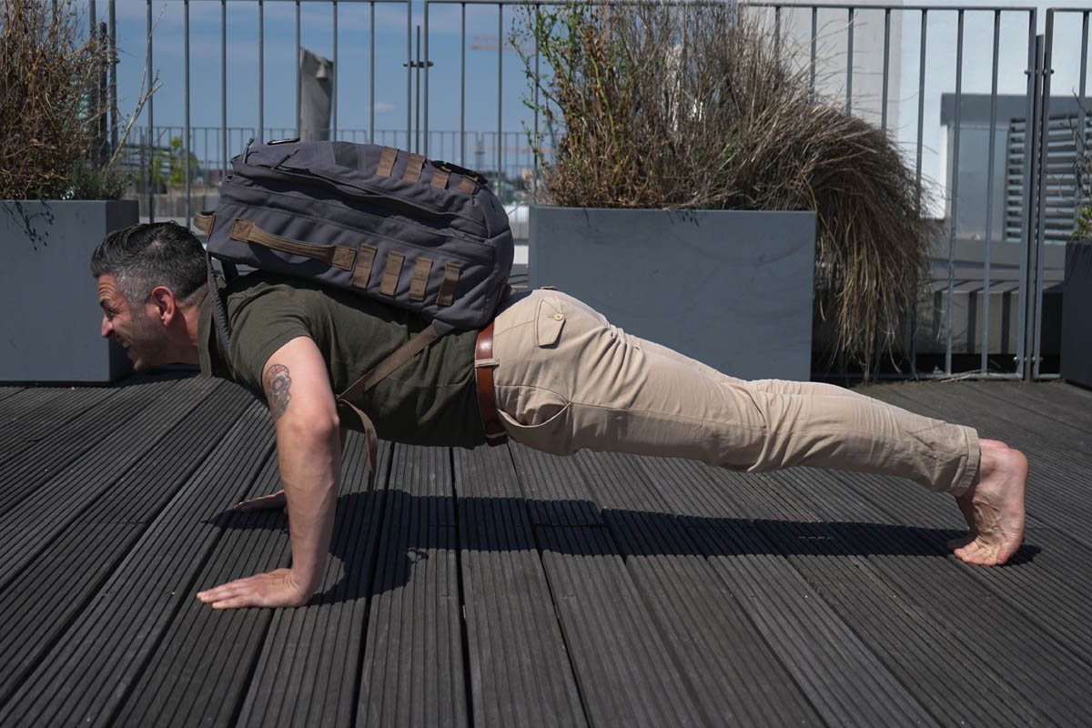 Ein Mann macht Liegestütze mit einem Rucksack.