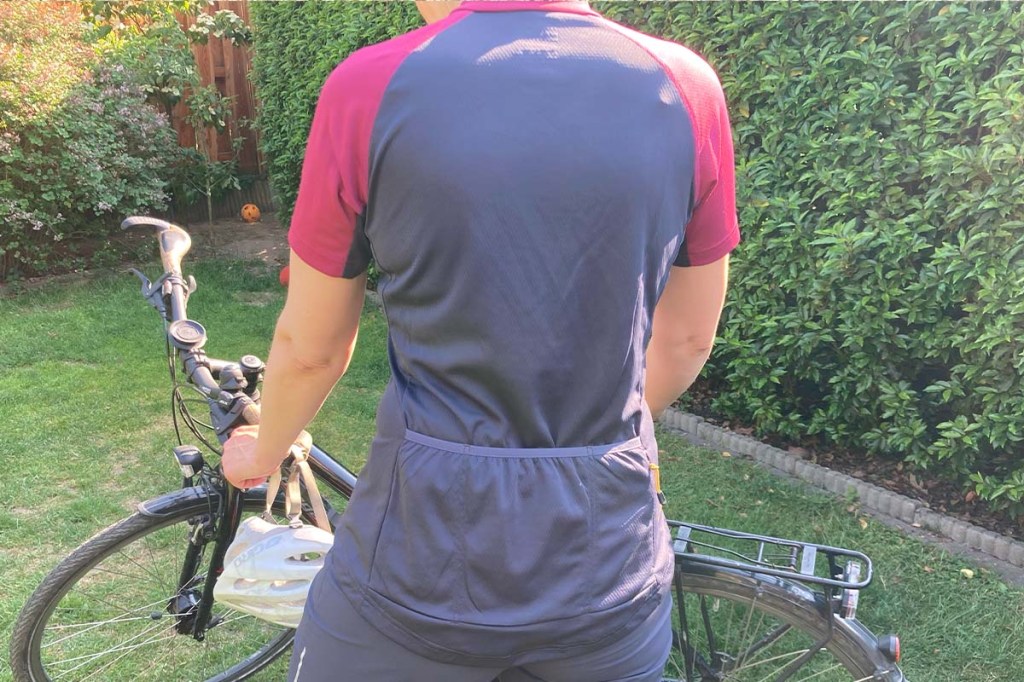 Frau von hinten Fokus auf das T-Shirt, welches sie trägt, Fahrrad im HIntergrund