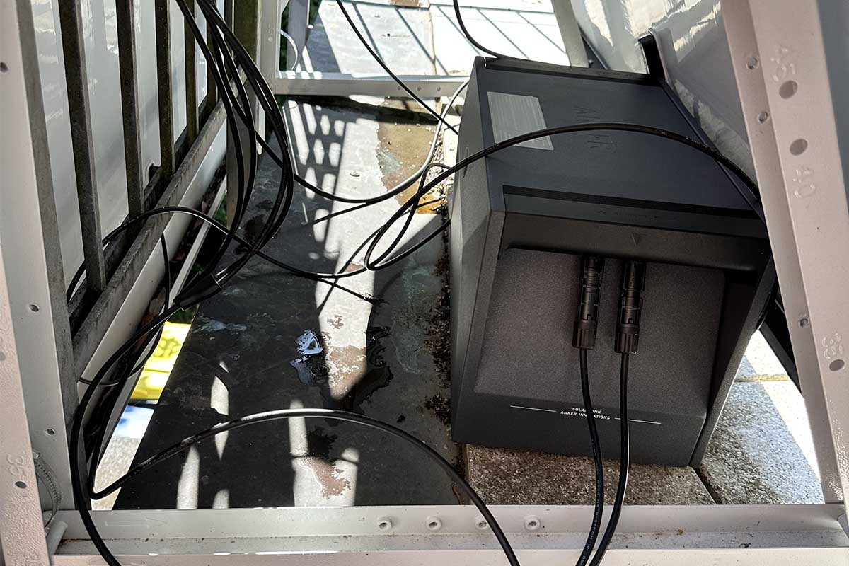 Die Solarbank E1600 von Anker mit angeschlossenen Kabeln und im Schatten des Solarpanels.