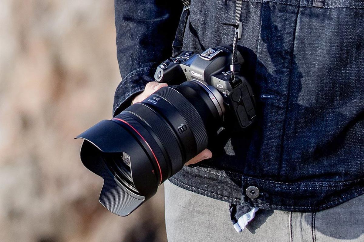 Objektiv und Kamera von Canon unter freiem Himmel in der Hand einer Person.