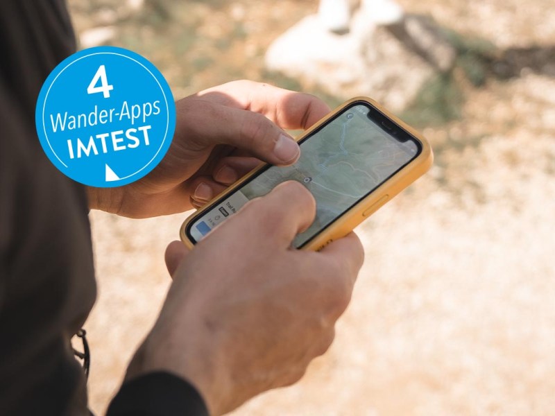 Smartphone mit geöffneter Komoot App unter freiem Himmel.