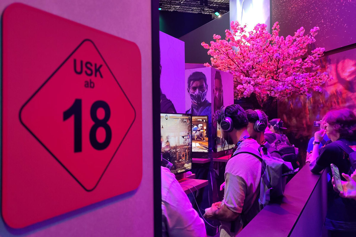 Foto von der Gamescom 23, man sieht ein USK-18-Logo vor dem Anspiel-Bereich von Mortal Kombat 1.