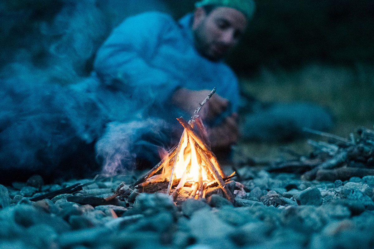 Ein Mann liegt an einem Lagerfeuer.