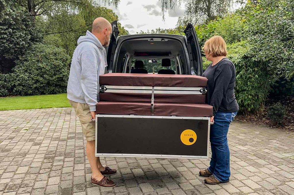 Zwei Personen tragen die QUQUQ-Box zum Auto.