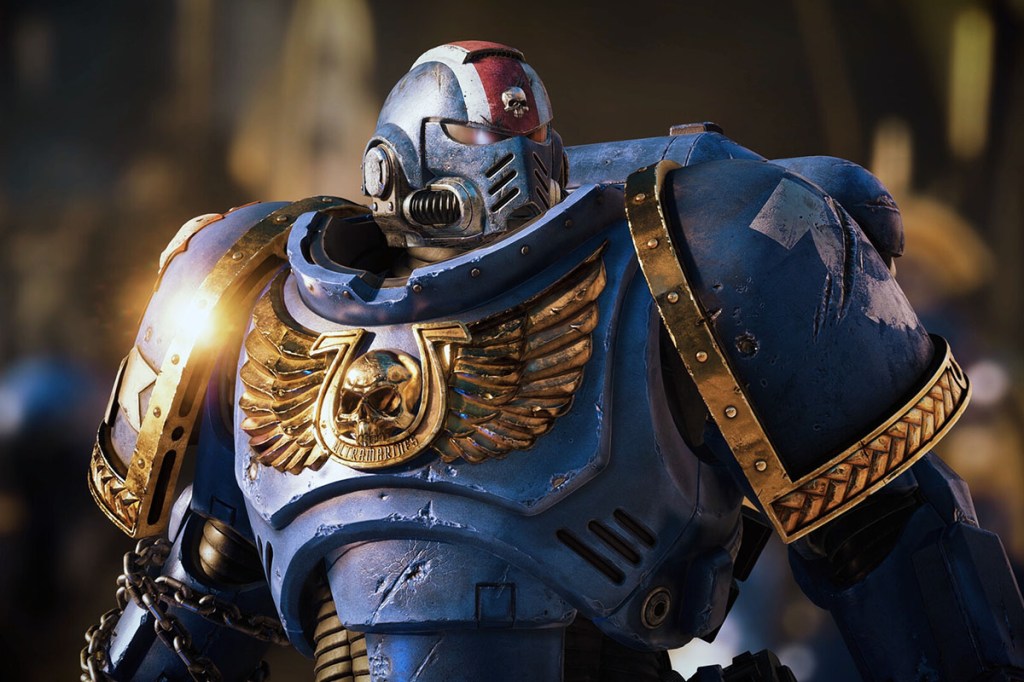Die Hauptfigur des Spiels Space Marine 2. Ein Blau gerüsteter Space Marine-Krieger mit Helm. Auf der Brust ein goldener Schädel mit Flügeln und Ordensabzeichen.