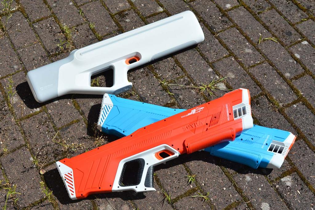 Foto dreier Wasserpistolen, einmal eine weiße von Xiaomi und eine blaue sowie eine rote von Spyra.