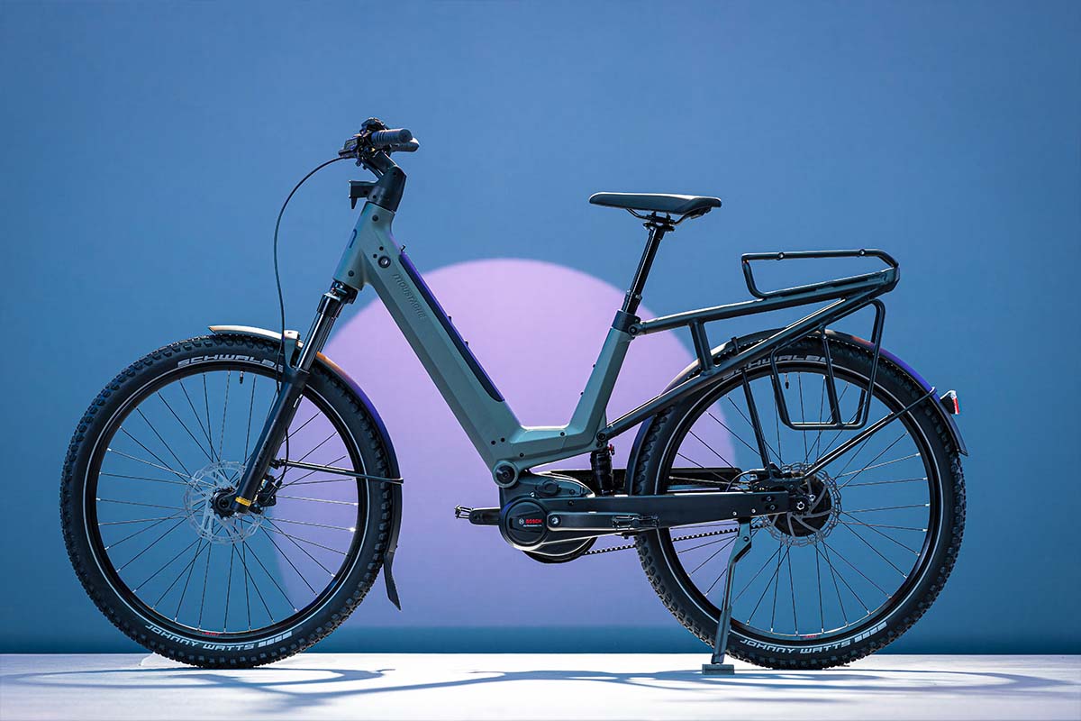 E-Bike J von Moustache auf einer Fläche stehend mit blauer Beleuchtung im Hintergrund, sowie die Silhoutte eines Monds