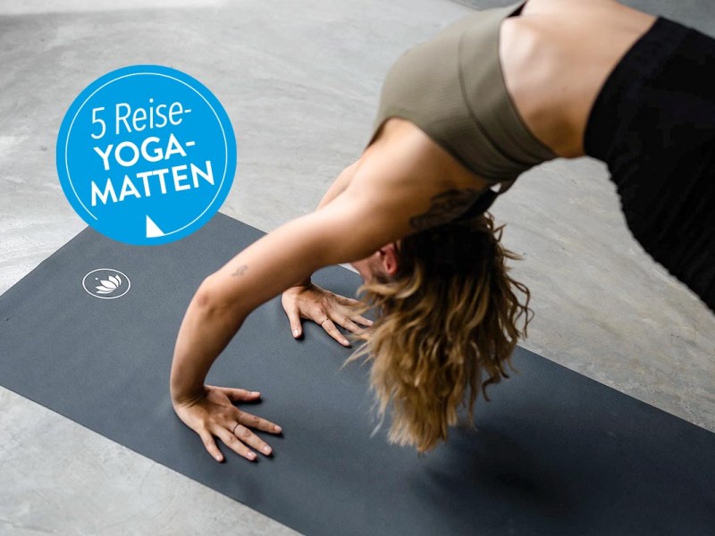 Person auf einer schwarzen Yogamatte auf dem Boden.