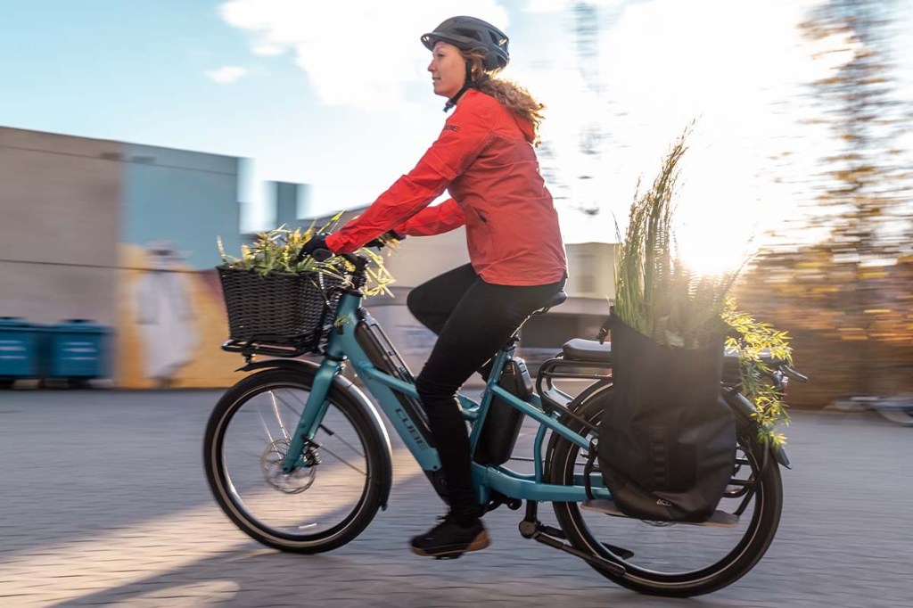 Frau fährt mit einem vollbeladenem E-Bike durch die Stadt