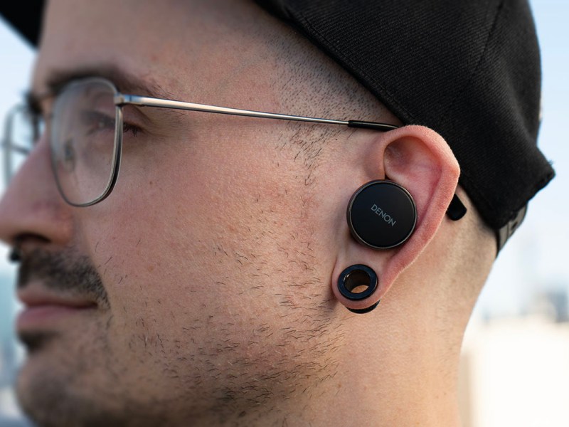 Der Testredakteur trägt die runden In-Ears Denon PerL Pro 182, seitlich fotografiert.