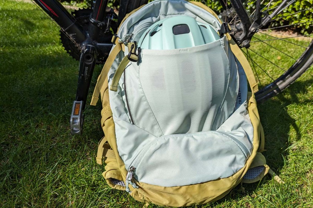 Nahaufnahme: Rucksack lehnt an einem Fahrrad, ein Helm steckt im Frontfach