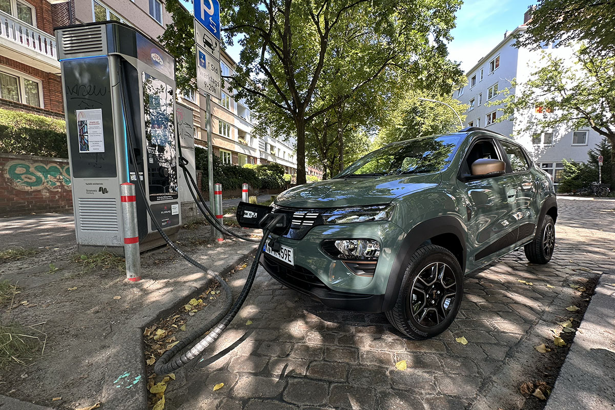 E-Auto Dacia Spring Extreme 65 beim Laden an einer Ladesäule in städtischem Gebiet.