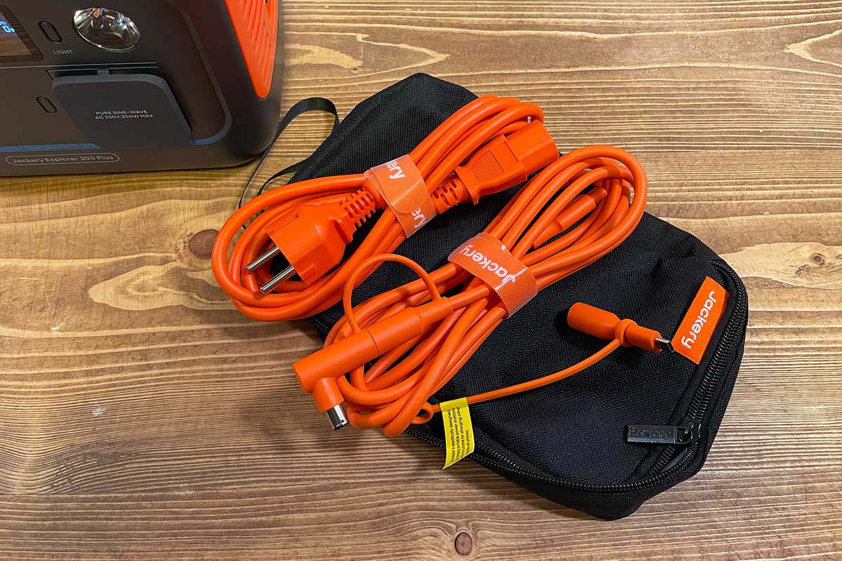 Zwei orangene Kabel und ein Adapter auf einer schwarzen Tasche.