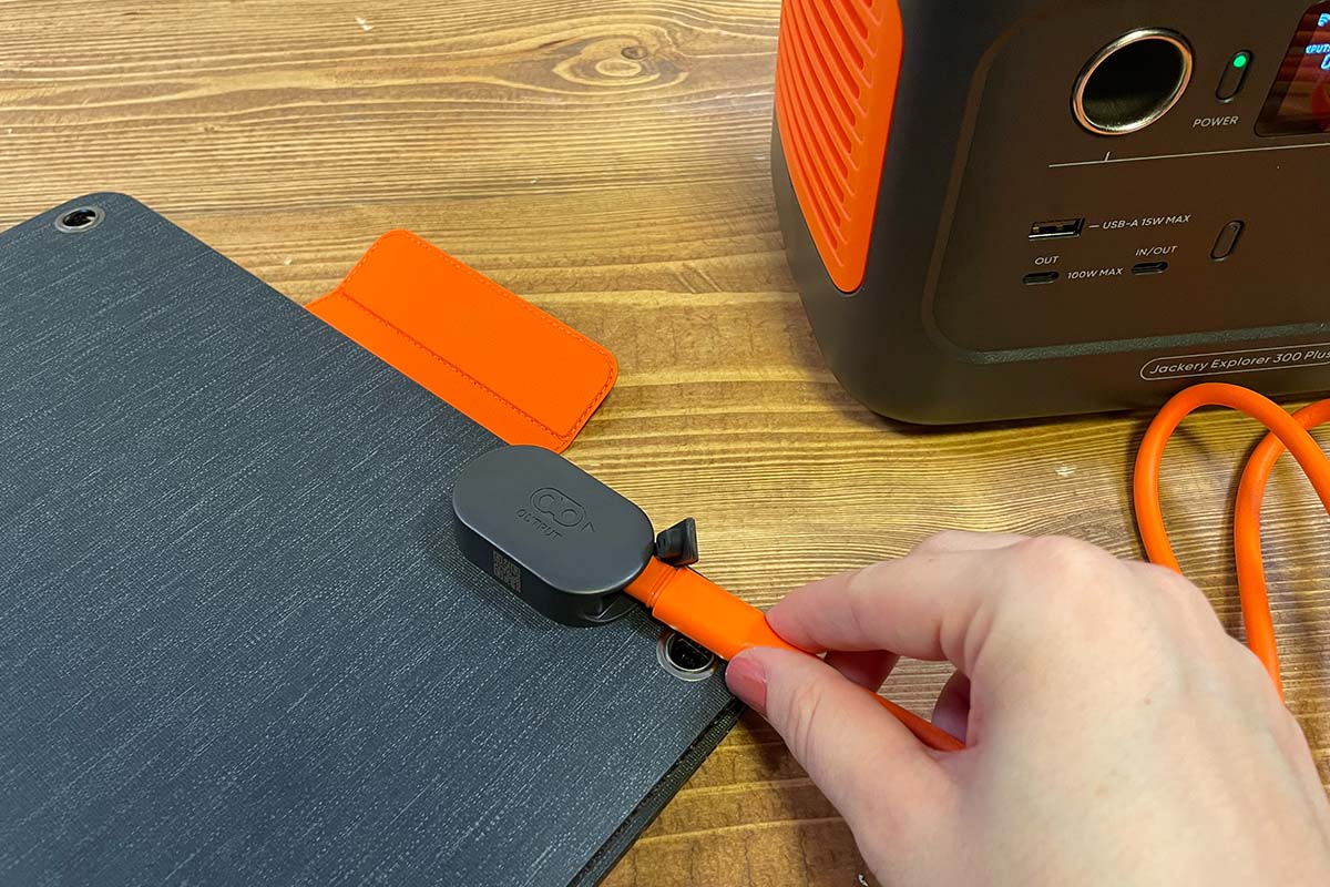 Eine Hand verbindet ein orangenes Kabel mit dem 40-Watt-Panel von Jackery.