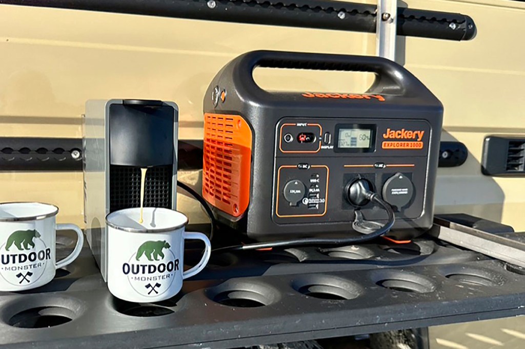 Powerstation vor Geländewagen auf einem Campingplatz.