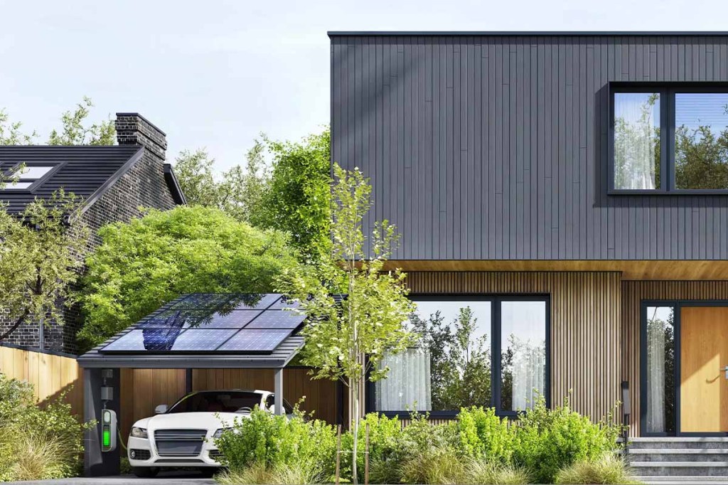 Vor einem Einfamilienhaus steht ein Solar-Carport, unter dem ein Elektroauto steht.