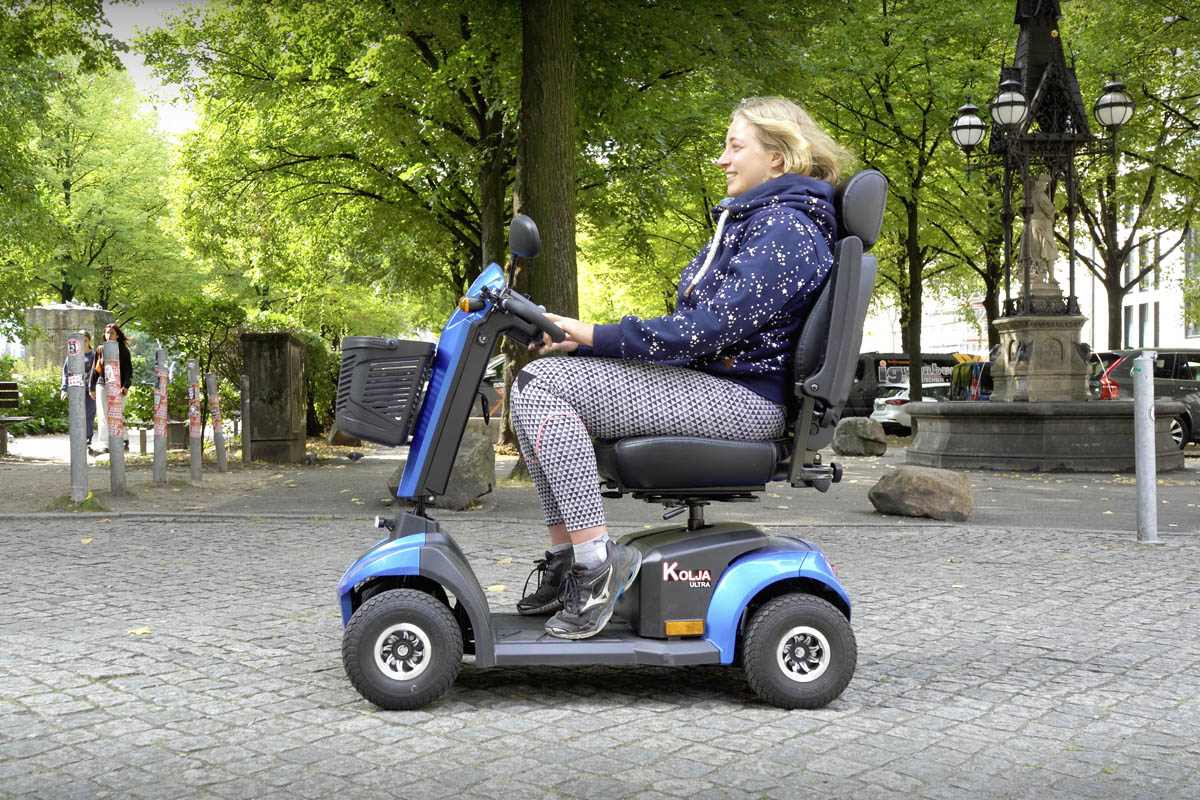 Eine blonde Frau fährt auf dem blauen Seniorenmobil Kolja Ultra.
