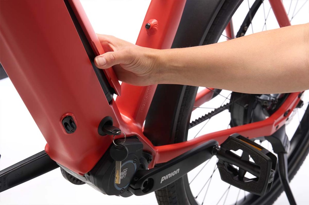 Nahaufnahme Rahmen E-Bike, Hand betätigt Schutzdeckel, worunter sich der Akku befindet