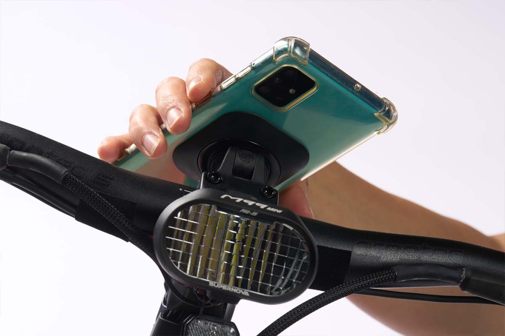 Nahaufnahme E-Bike-Lenker, Hand rastet Smartphone auf Halterung ein