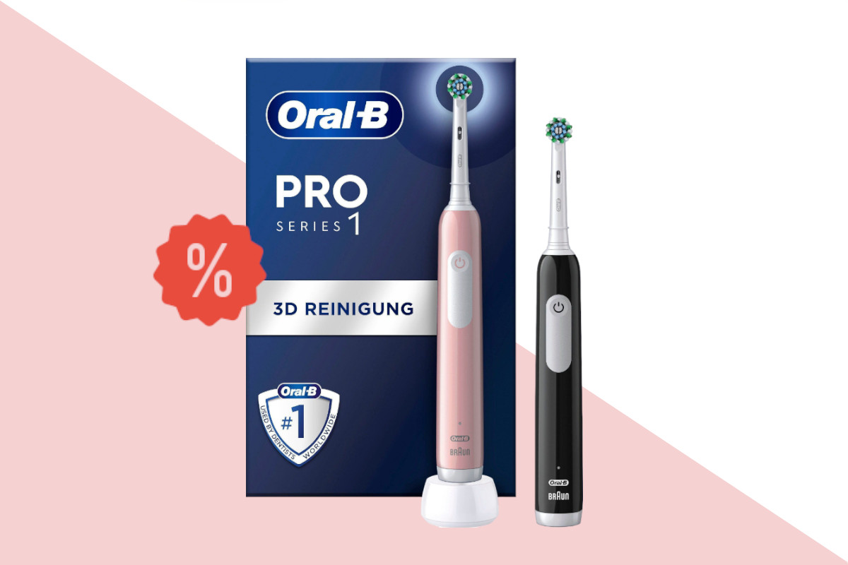 Zwei elektrische Zahnbürsten Oral-B Pro 1 versetzt nebeneinander von vorne in rosa und schwarz vpr blau weißem Karton auf rosa weißem Hintergrund mit rotem Prozentzeichen links mittig