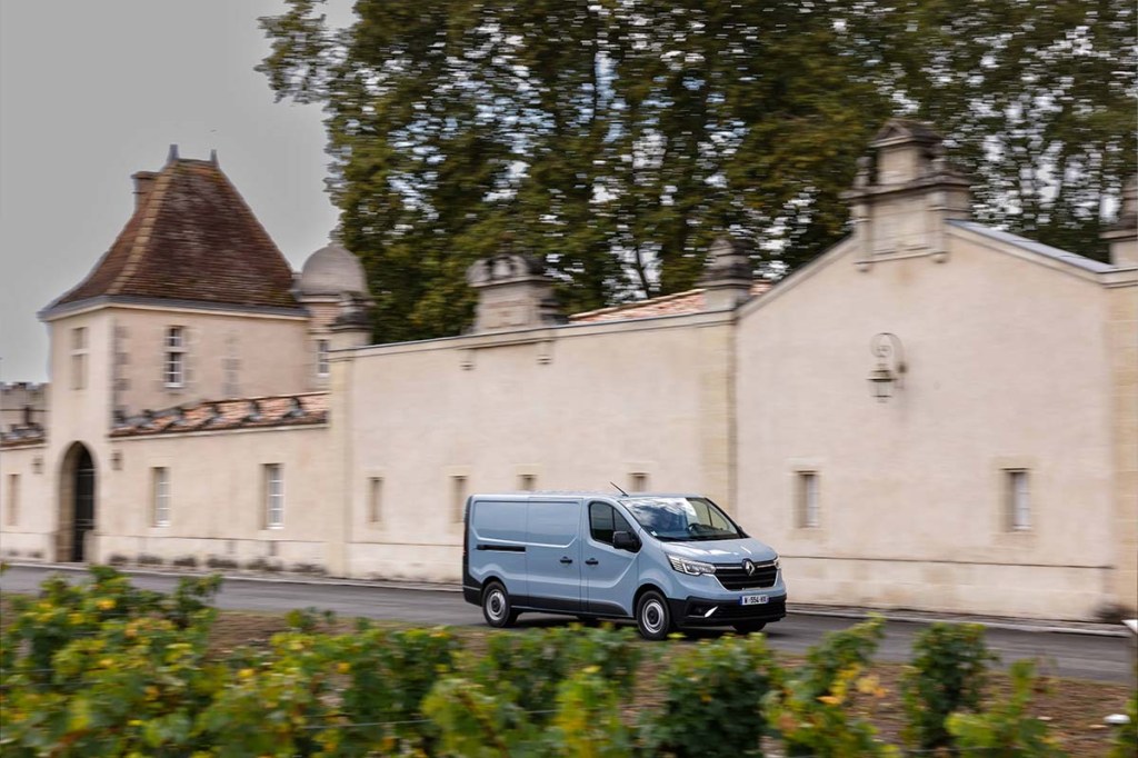 Totale, blauer Renault-Kastenwagen fährt an einer Burg vorbei