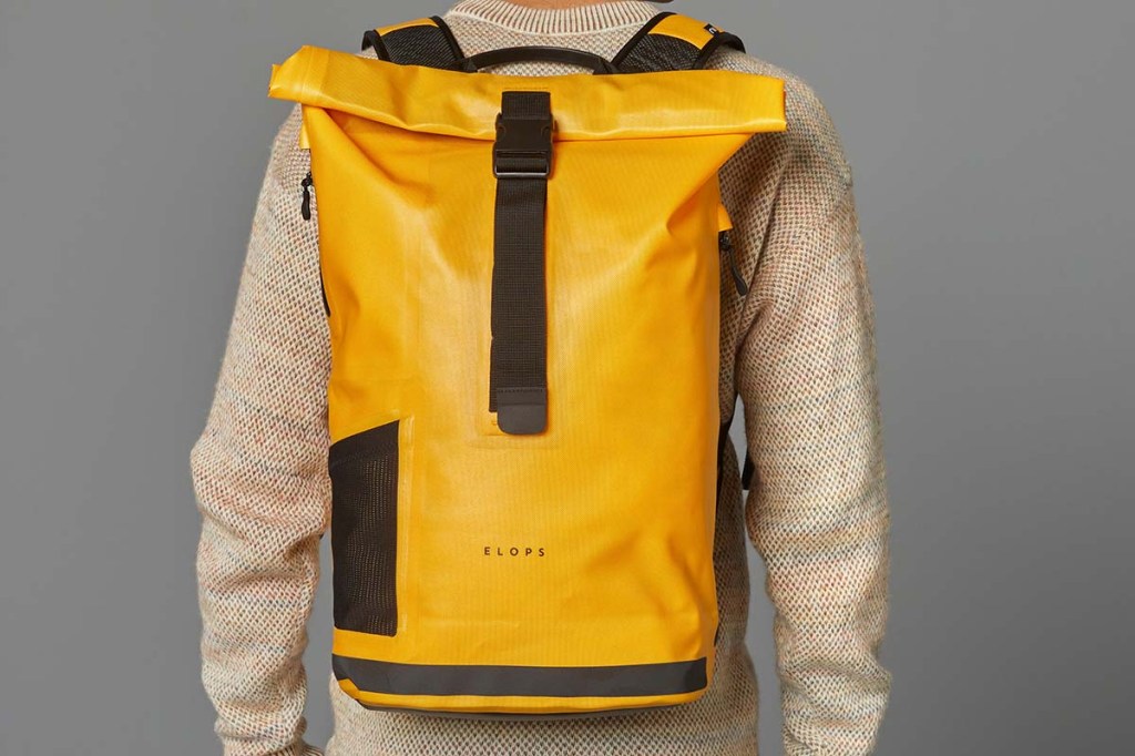 Person von hinten im Anschnitt, hat einen gelben Rucksack auf dem Rücken, dem man komplett sieht