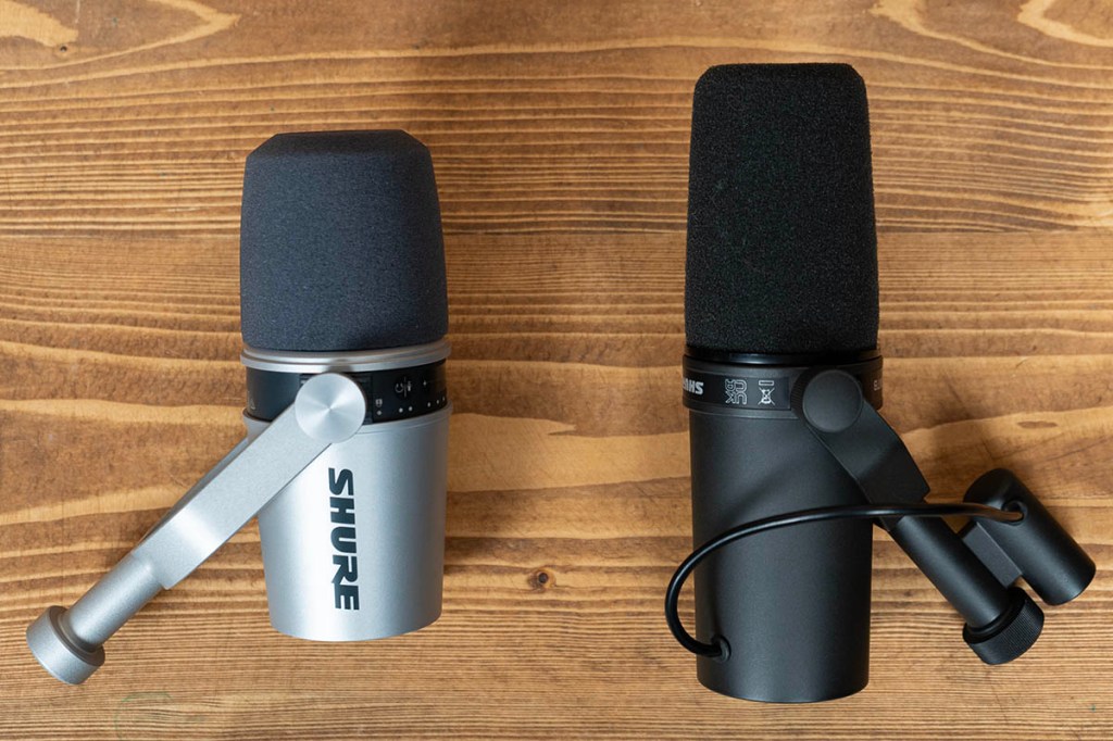 Die Studio-Mikrofone Shure MV7 und SM7B liegen nebeneinander auf einem Holztisch. Das linke Mikrofon ist silber, das rechte schwarz.