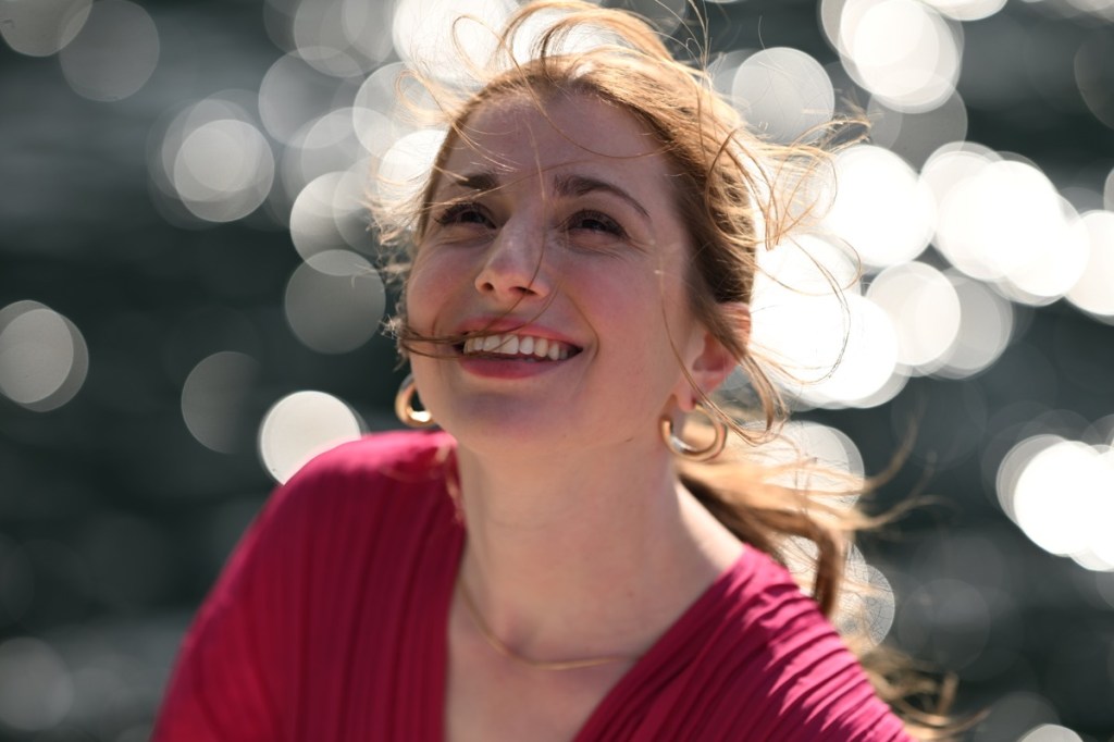 Aufnahme einer lächelnden Frau mit Glanzlichtern im unscharfen Hintergrund