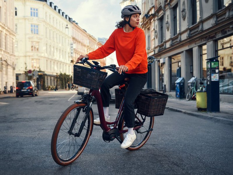 Frau fährt mit E-Bike Riese & Müller Swing4 über eine Straße in der Stadt.