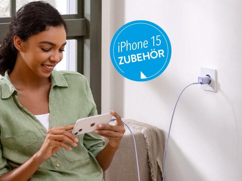 Person mit iPhone in der Hand, das an einem Kabel angeschlossen ist.