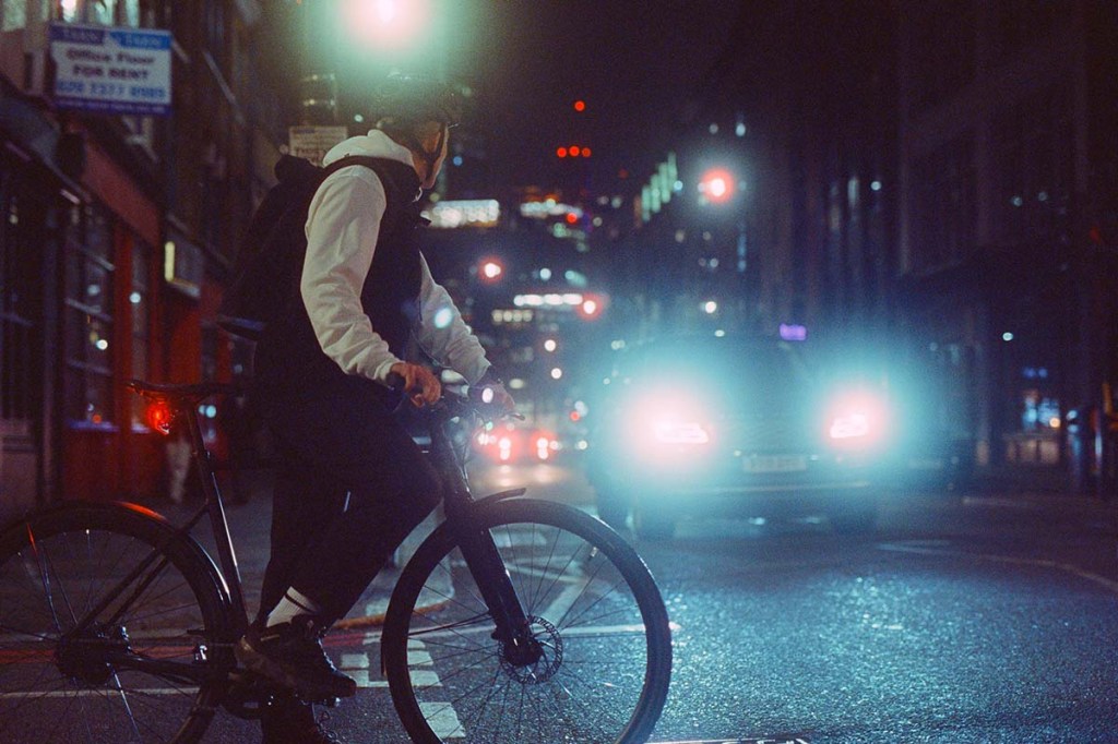 Person mit E-Bike im nächtlichen Stadtverkehr