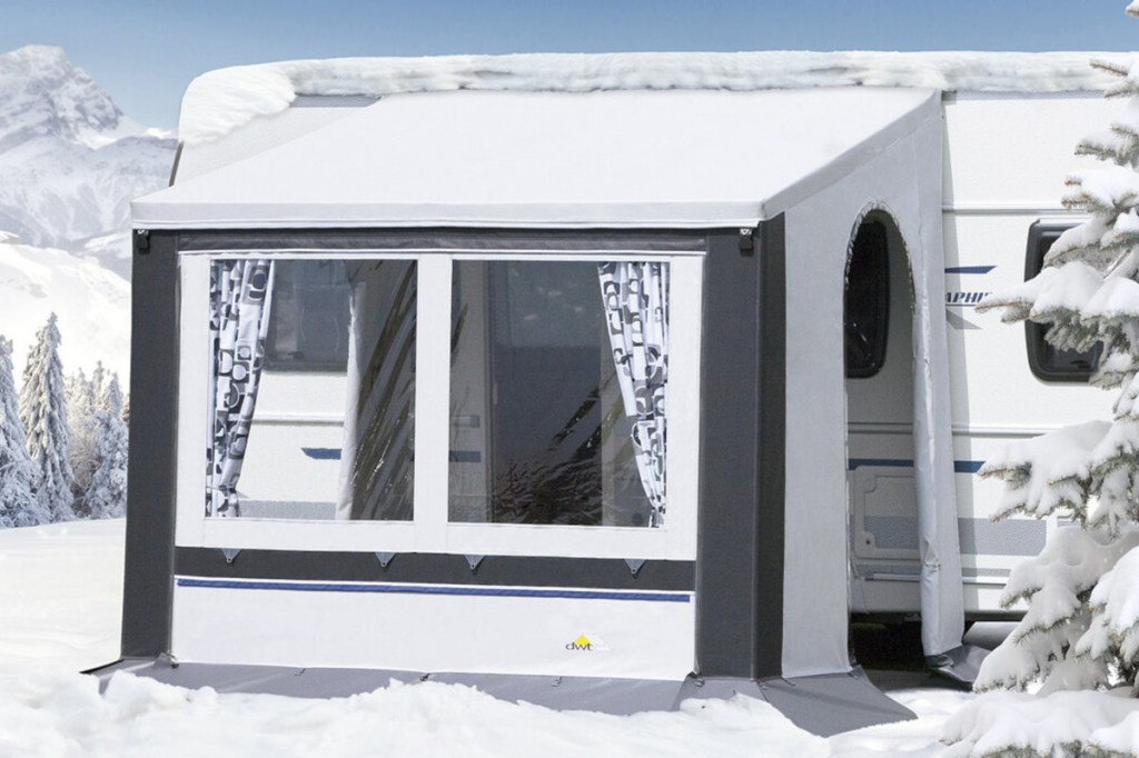 Weiß graues kurzes DWT-Vorzelt schräg von vorne vor weißem Wohnmobil in bergiger Winterlandschaft