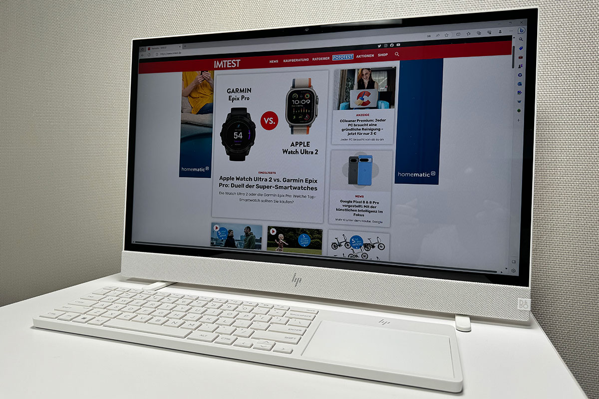 Der All-in-one-Computers HP Envy Home steht auf einem Arbeitsplatz, auf dem Bildschirm ist die Webseite IMTEST.de zu sehen.