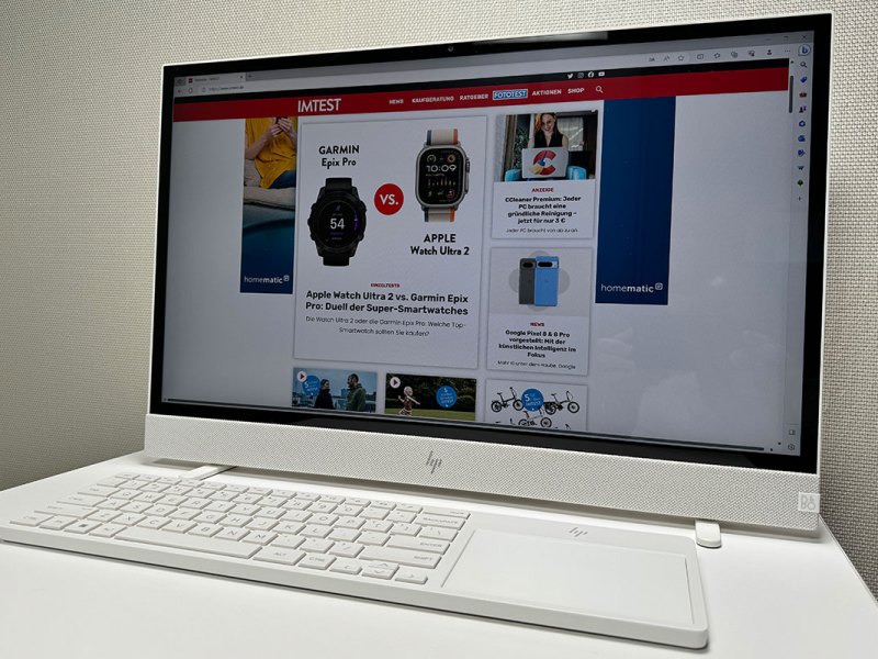 Der All-in-one-Computers HP Envy Home steht auf einem Arbeitsplatz, auf dem Bildschirm ist die Webseite IMTEST.de zu sehen.