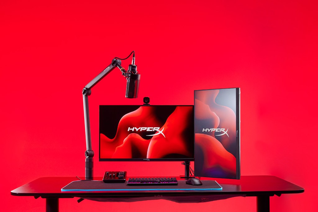 Mikrofon-Arm, Audio-Mixer und Webcam der Marke HyperX an einem schicken PC-Arbeitsplatz.