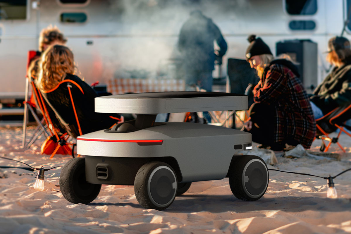 Der neue Solar Mars Bot auf einem Sandstrand. Im Hintergrund eine Camping-Szene mit Lagerfeuer.
